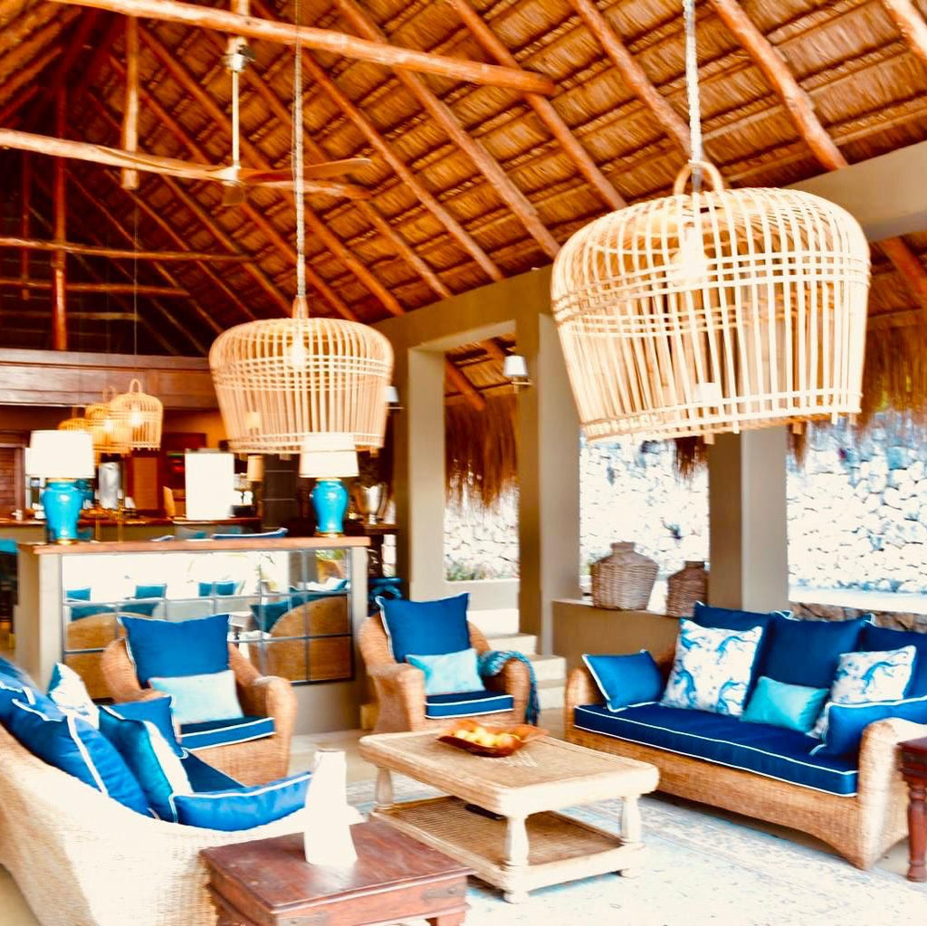 Modern living room with blue cushions on furniture, wooden ceiling, and decorative lamps.