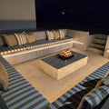Modern outdoor seating area with striped cushions, a fire pit table, and a large screen TV.