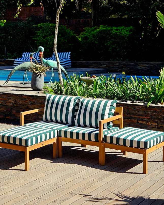 Outdoor patio set with green striped cushions by a poolside