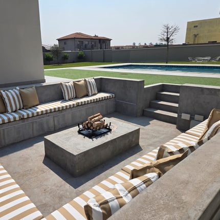 Outdoor patio with concrete seating area, fire pit, and striped cushions.