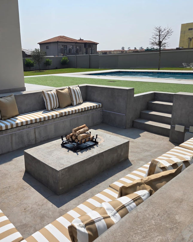Outdoor patio with concrete seating area, fire pit, and striped cushions.