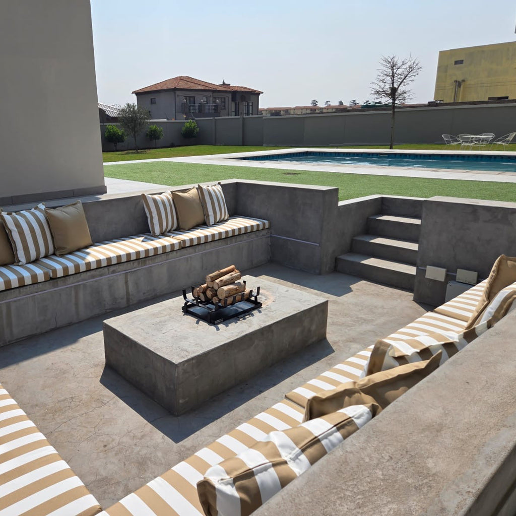 Outdoor patio with concrete seating area, fire pit, and striped cushions.